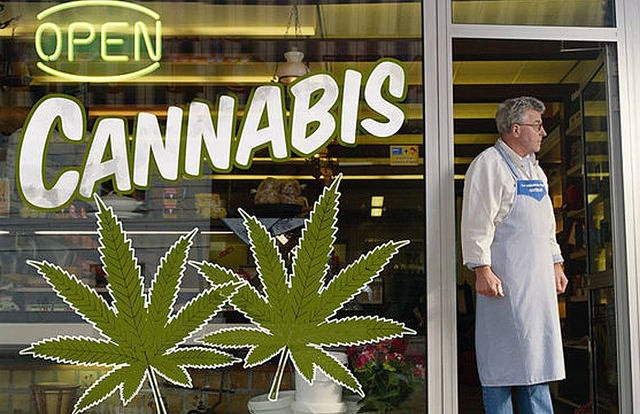 Open sign on cannabis dispensary storefront with man standing in entrance