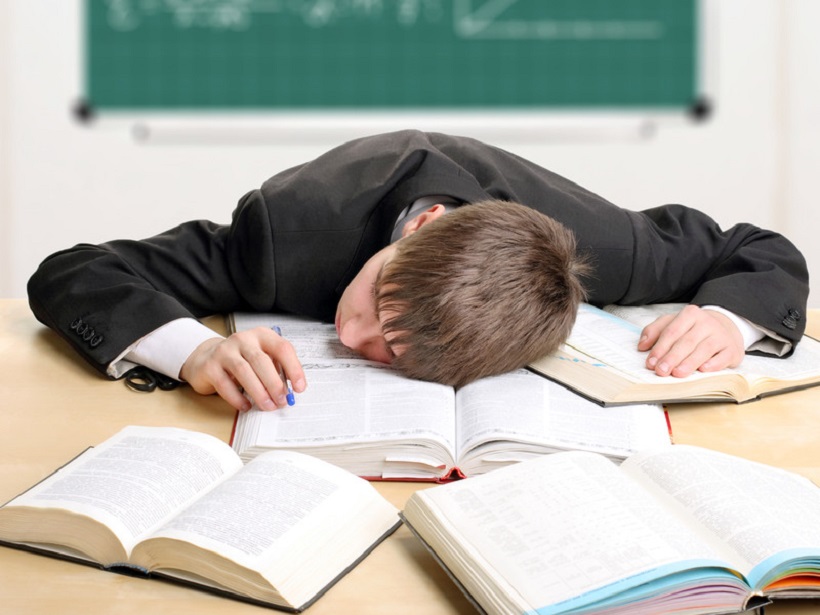 Top Cannabis Strains to Battle Fatigue and Stress. Student with head on desk.