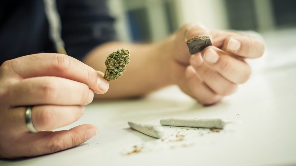 Best Ways To Improve Cannabis Flavor. A person holding a bud and chocolate over two spliffs.