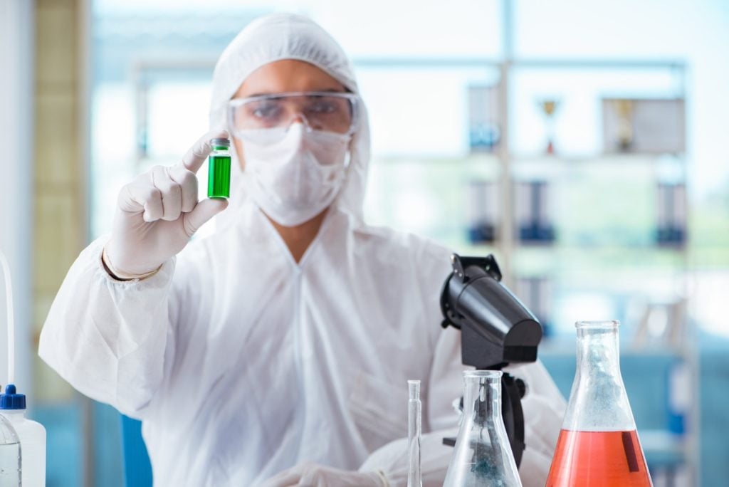 Reasons Why Cannabis Testing Is Important. A lab technician holding a vial of some green liquid.