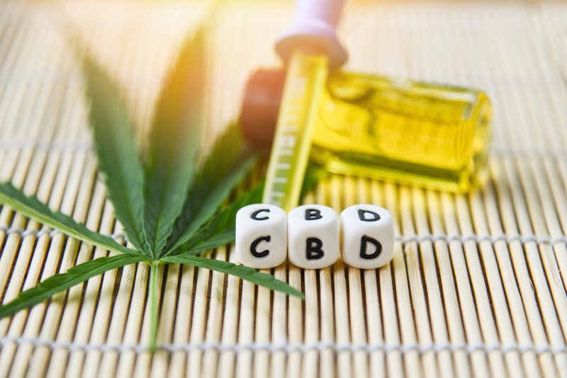 letters making up the word cbd next to oil and marijuana leaves, choosing cbd oil