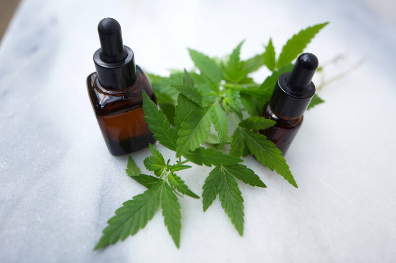 cbd oil tinctures next to marijuana leaves, use cbd products to improve your mental health