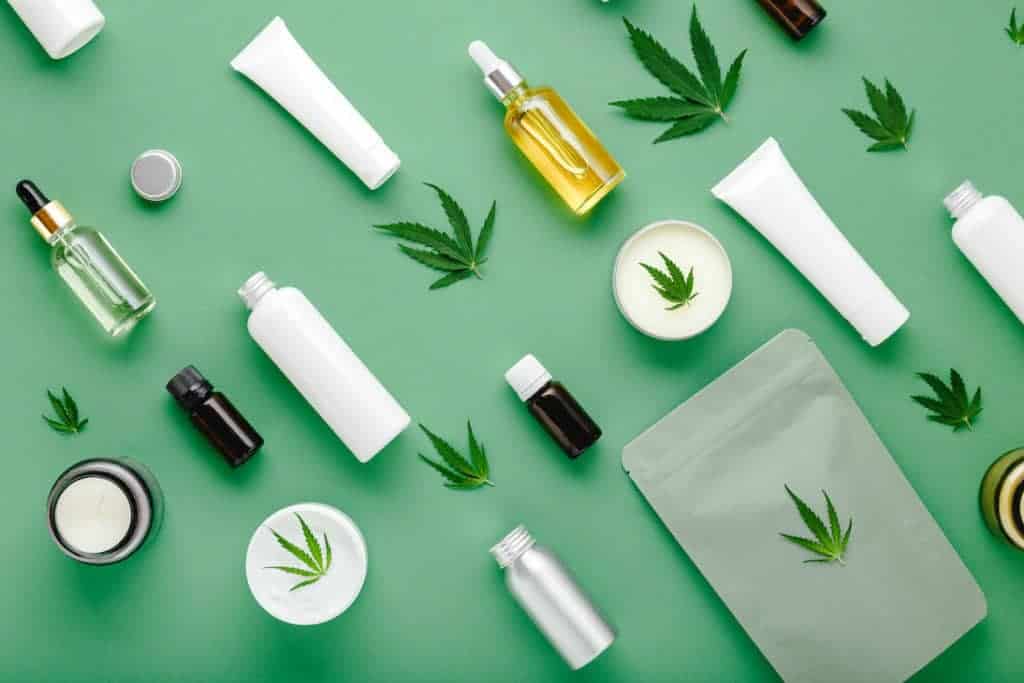 cbd oil in glass dropper bottle with cannabis leaves and lotion laying flat