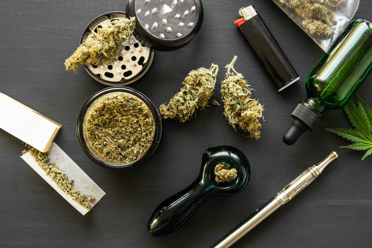 cannabis flower on black table with lighter, bong, papers and tincture, tips and tricks for weed smokers