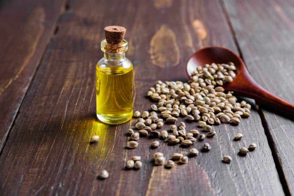 Hemp oil in bottle and seeds on wooden background