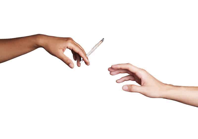 hand handing off a joint, smoking weed